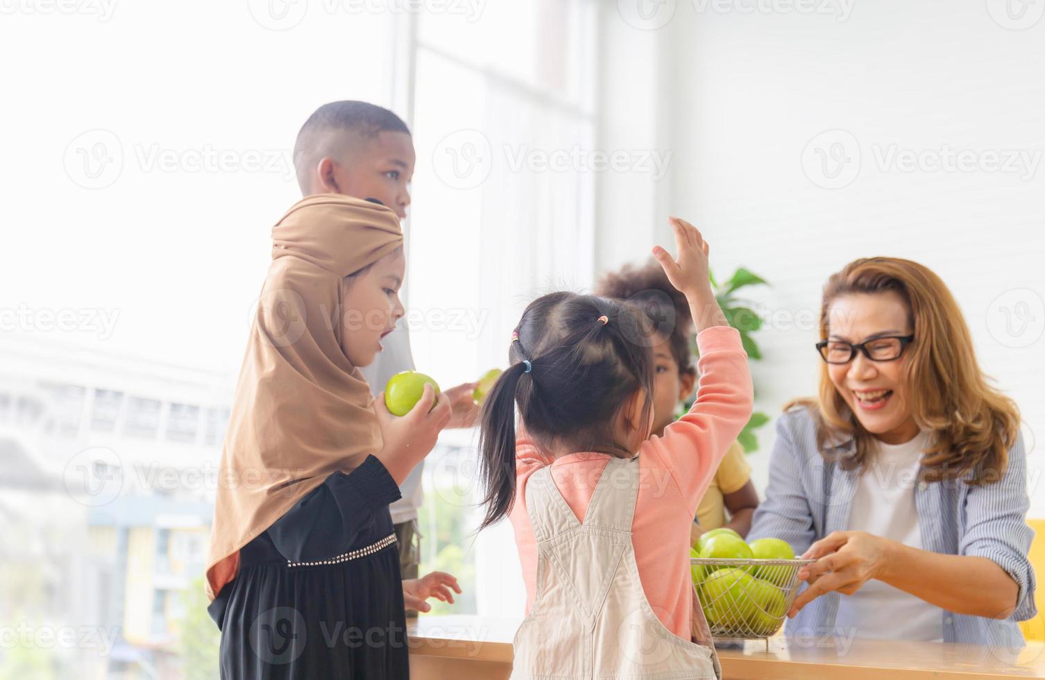 Mom and kids with apple, grandchildren and grandmother playing cheerfully in living room photo