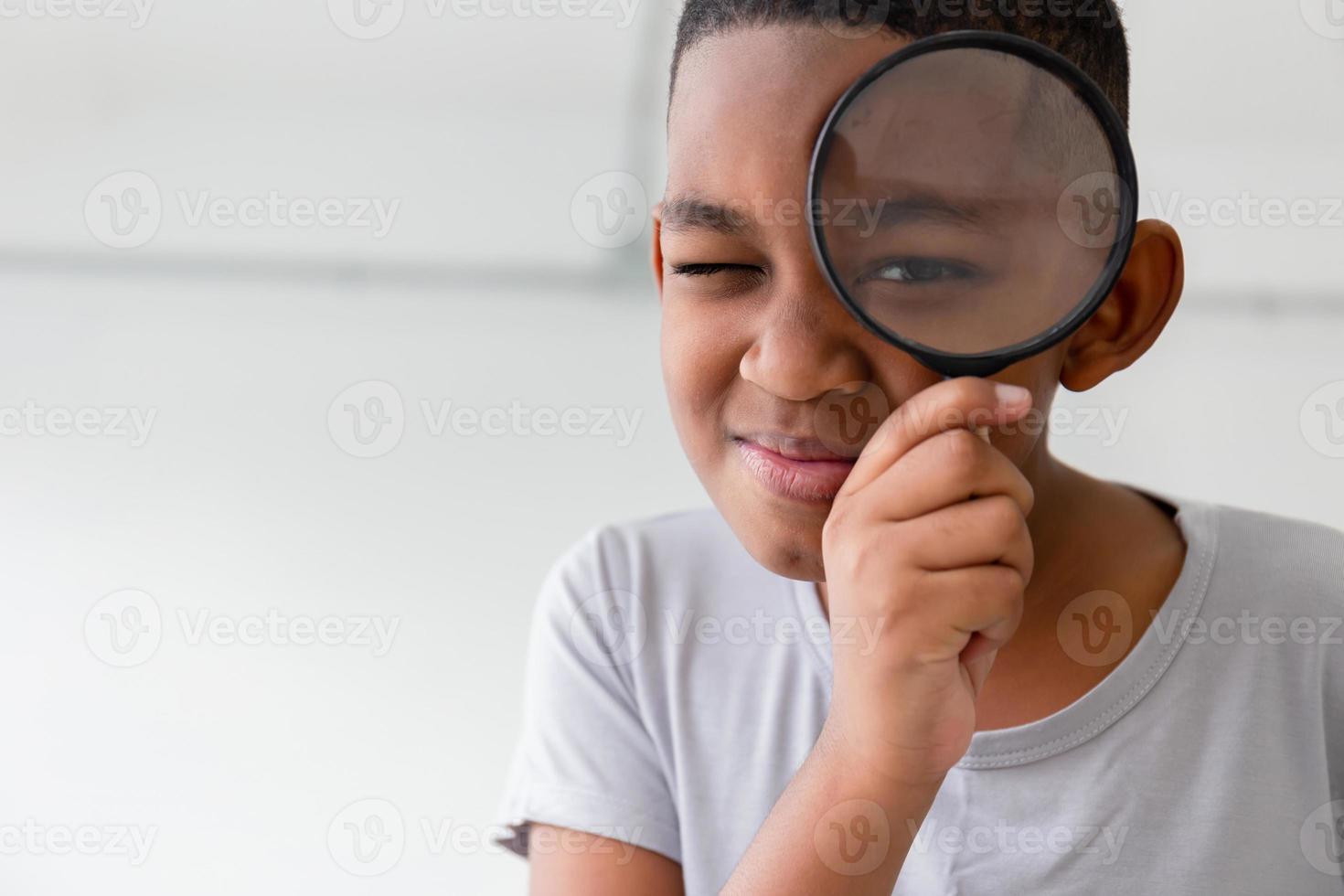 Smiling kid boy playing cheerfully with magnifying glass photo