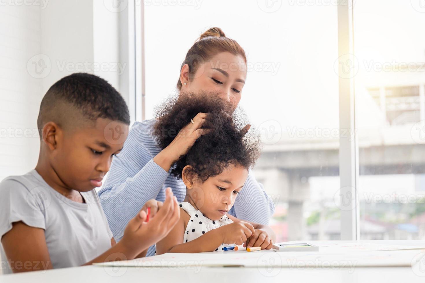 Children and grandmother drawing together pictures at home, Mother daughter and son playing cheerfully in living room photo