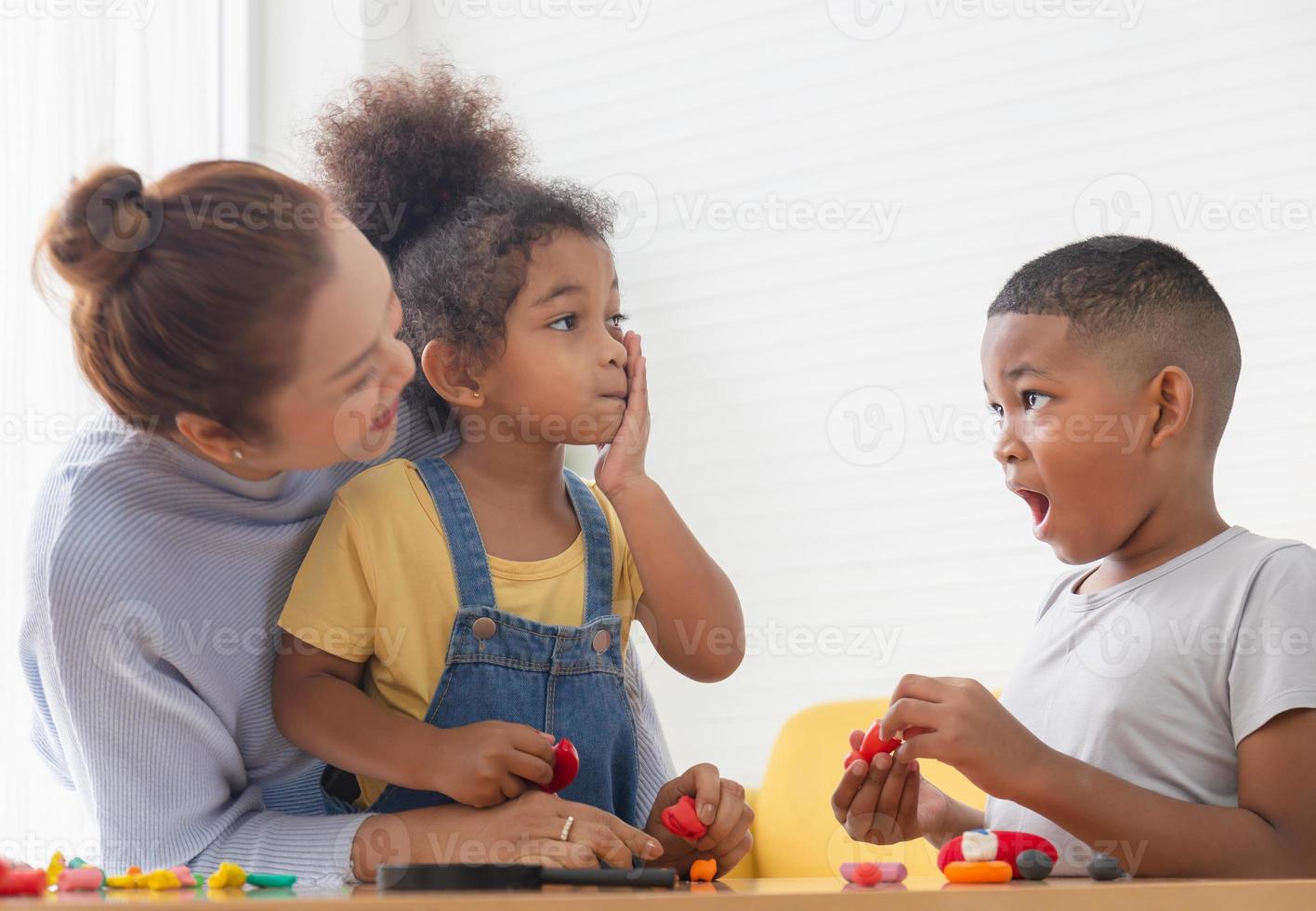 Children playing game with grandparents in living room, Grandchildren mould from plasticine with grandmother photo