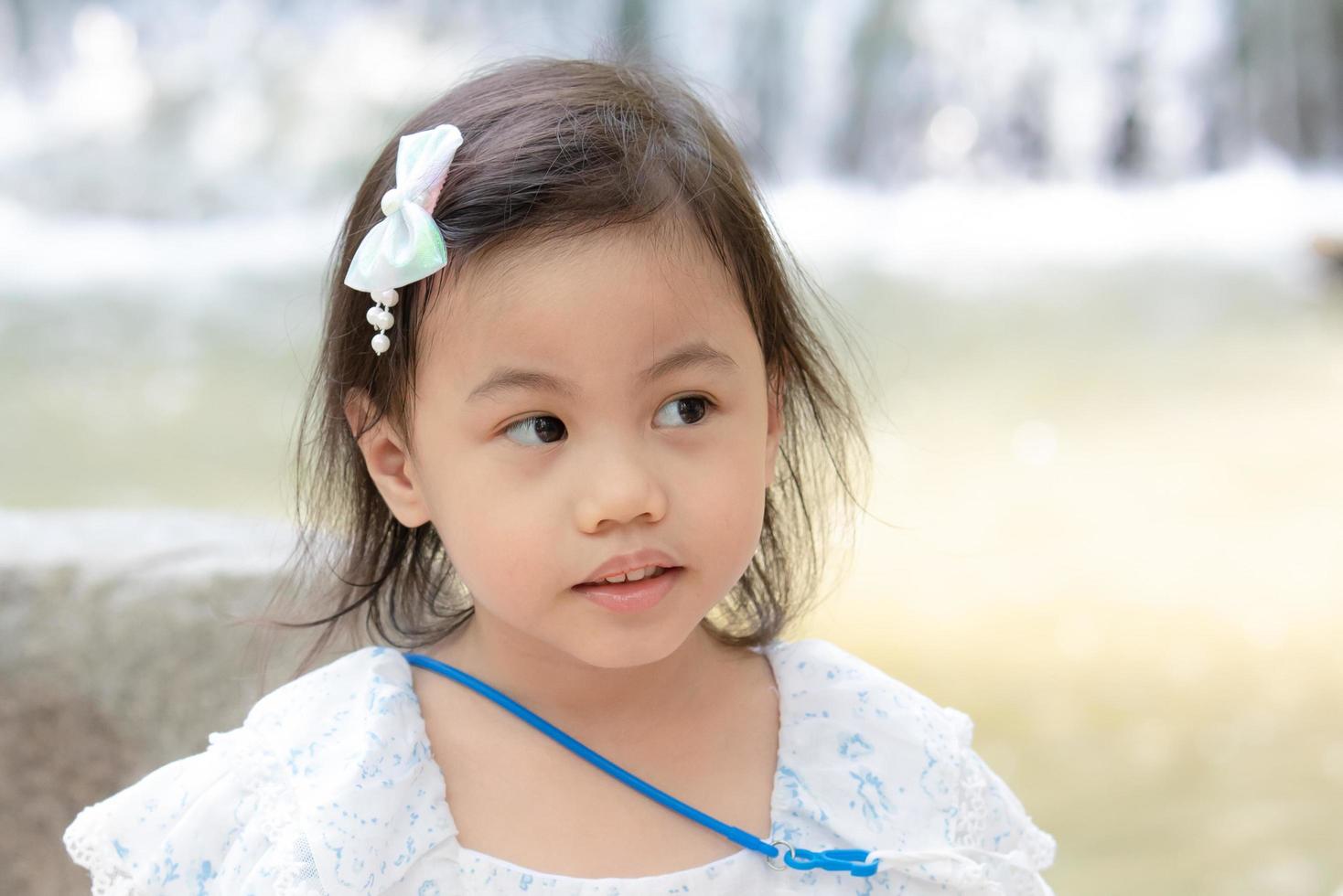 Positive charming 4 years old cute baby Asian girl, little preschooler child looking to the right at copy space. photo