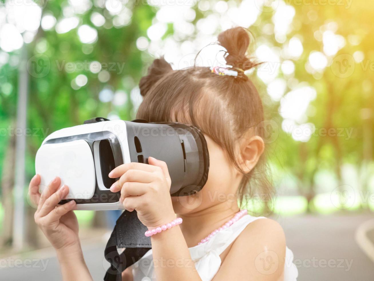 Outdoor park green garden public girl child baby woman female wear red simulator headset virtual reality technology digital video cyber network media information data analysis entertainment display photo