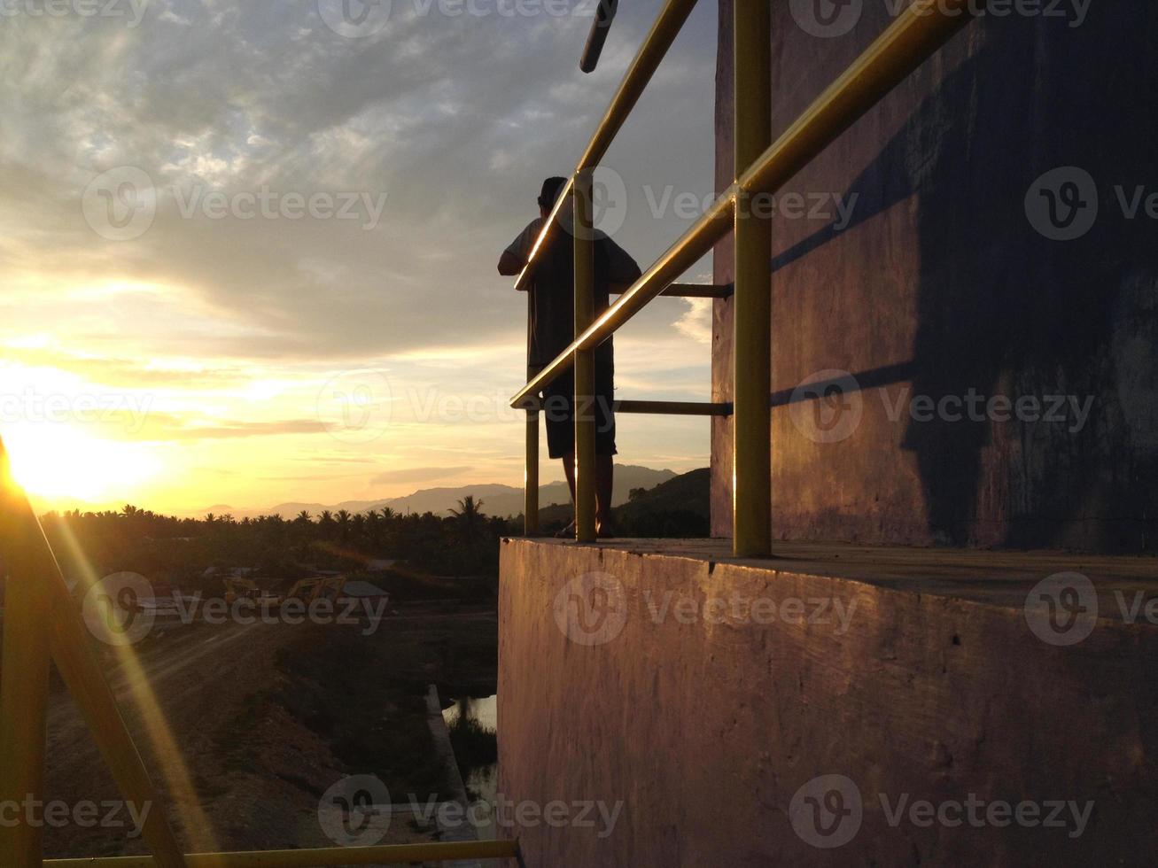 una vista trasera del hombre contra un fondo de cielo naranja foto