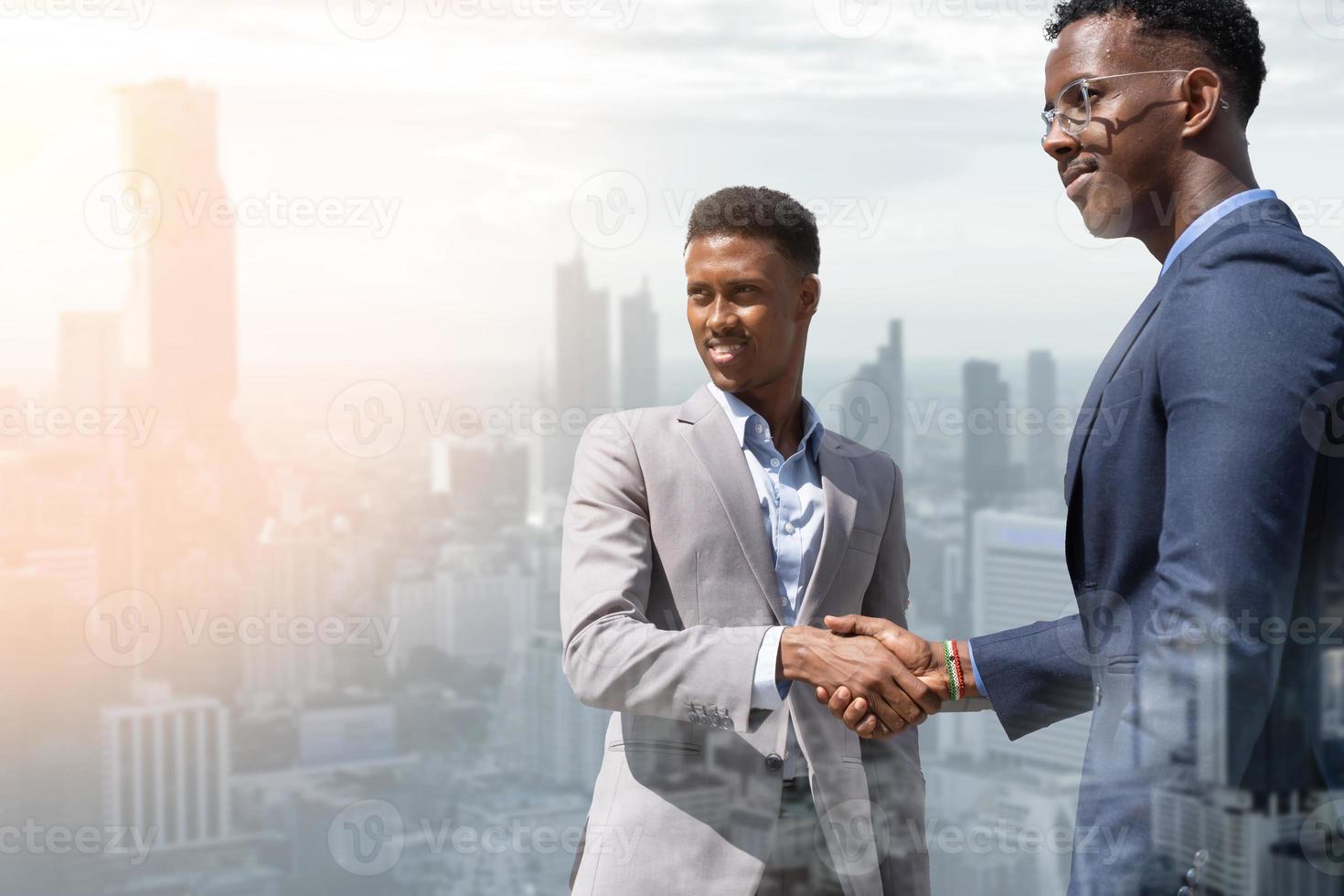 bienvenido a nuestro equipo. jóvenes modernos con ropa informal elegante dándose la mano. dos hombres de negocios sonrientes dándose la mano. dos hombres de negocios confiados dándose la mano y buscando el futuro. foto