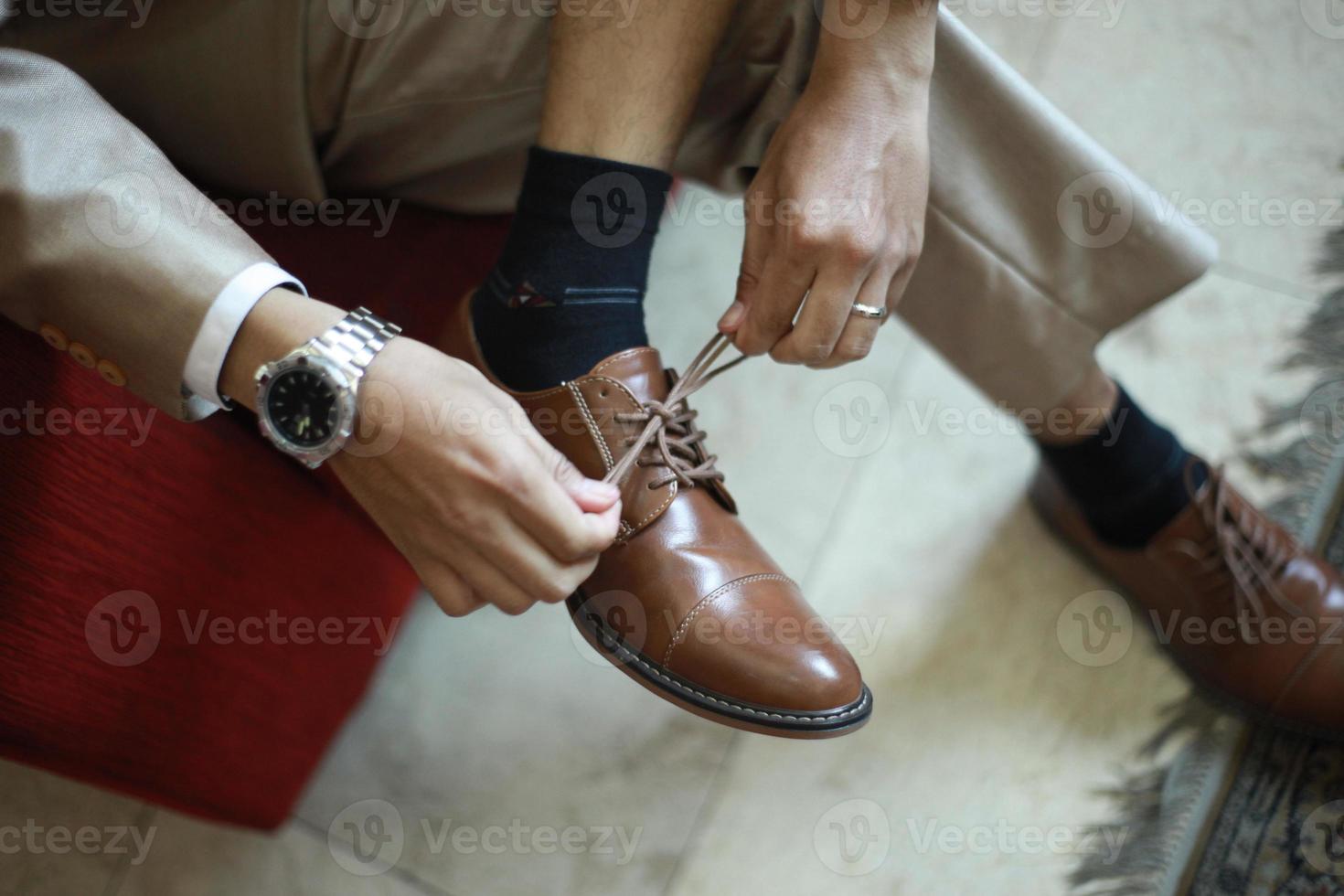 Manos de hombre atando cordones de zapatos marrones versión horizontal foto