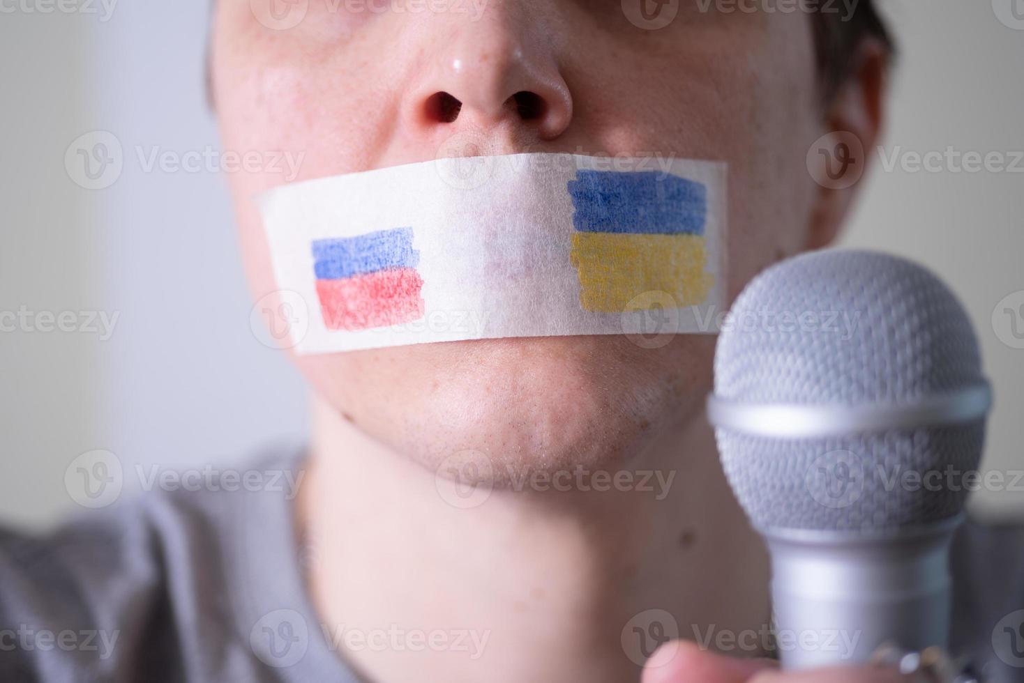 A duct-taped mouth with a flag of Russia and Ukraine trying to speak into a microphone. photo