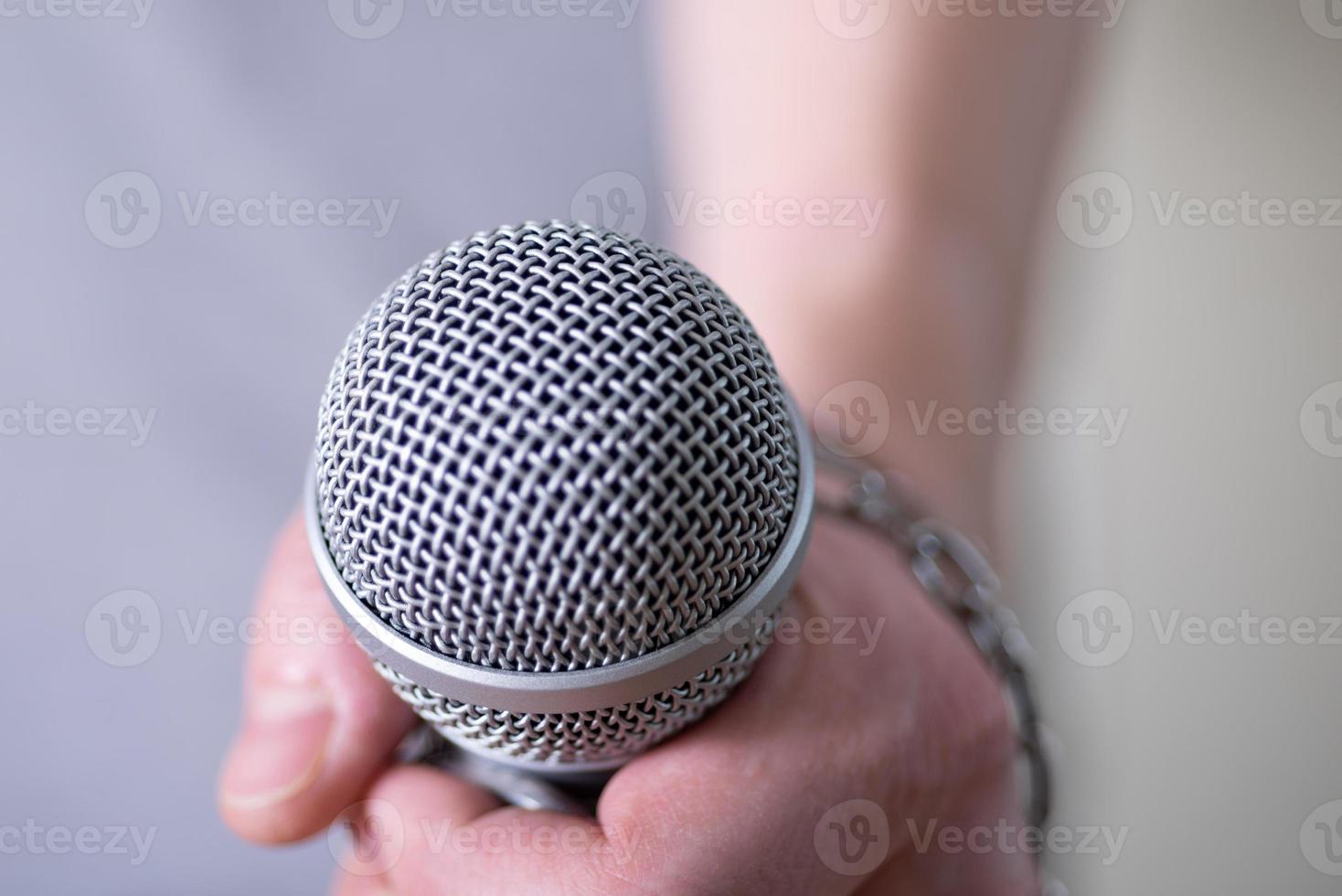 Dynamic microphone close-up on dark background, the chain on his arm. photo