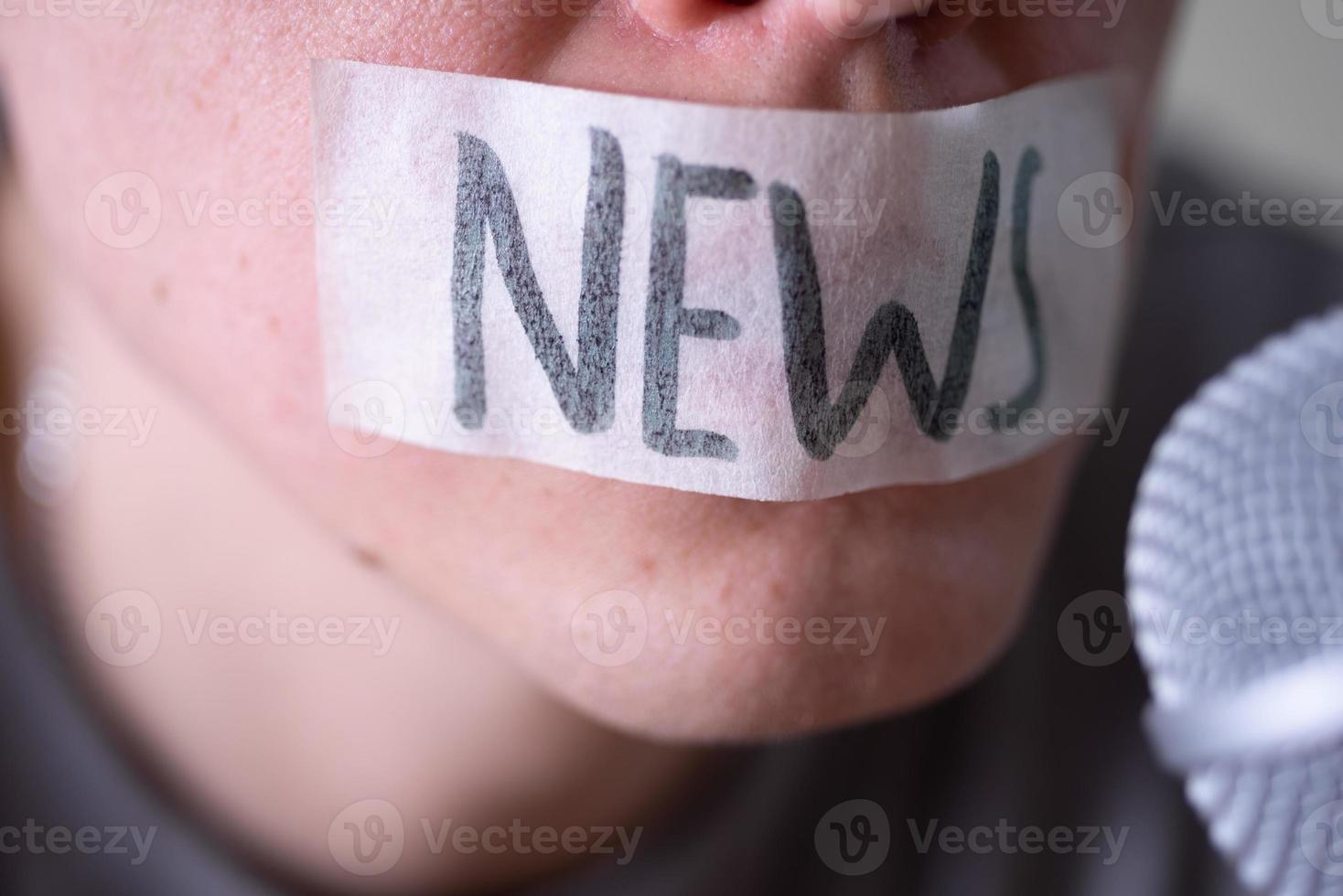 un hombre se amordaza la boca con cinta adhesiva diciendo noticias tratando de hablar por un micrófono. foto