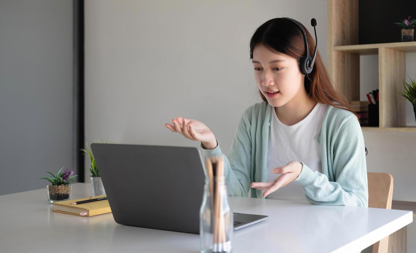 Asian student in casual clothes explaining homework on video conference with teachers on laptop computers at home photo