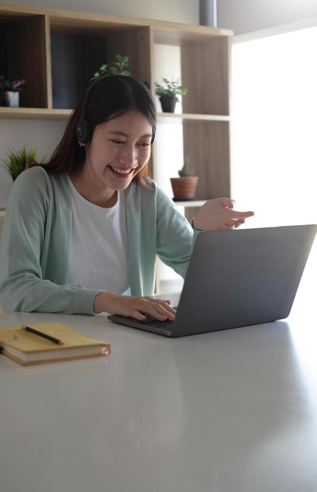 Asian student in casual clothes explaining homework on video conference with teachers on laptop computers at home photo