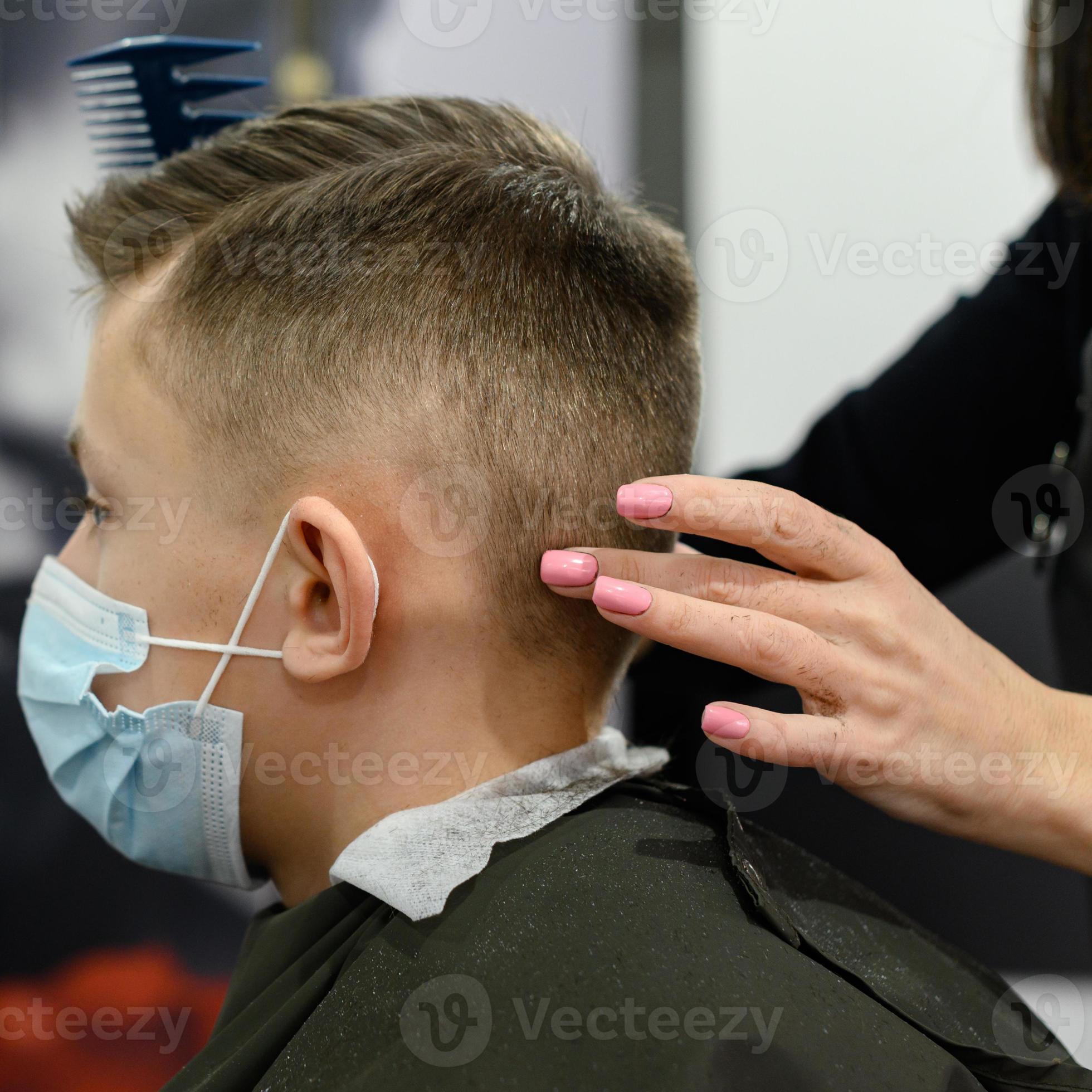 A teenage boy gets a haircut in a barbershop during a pandemic, a haircut  in a salon, a client and a hairdresser in masks. 7291536 Stock Photo at  Vecteezy