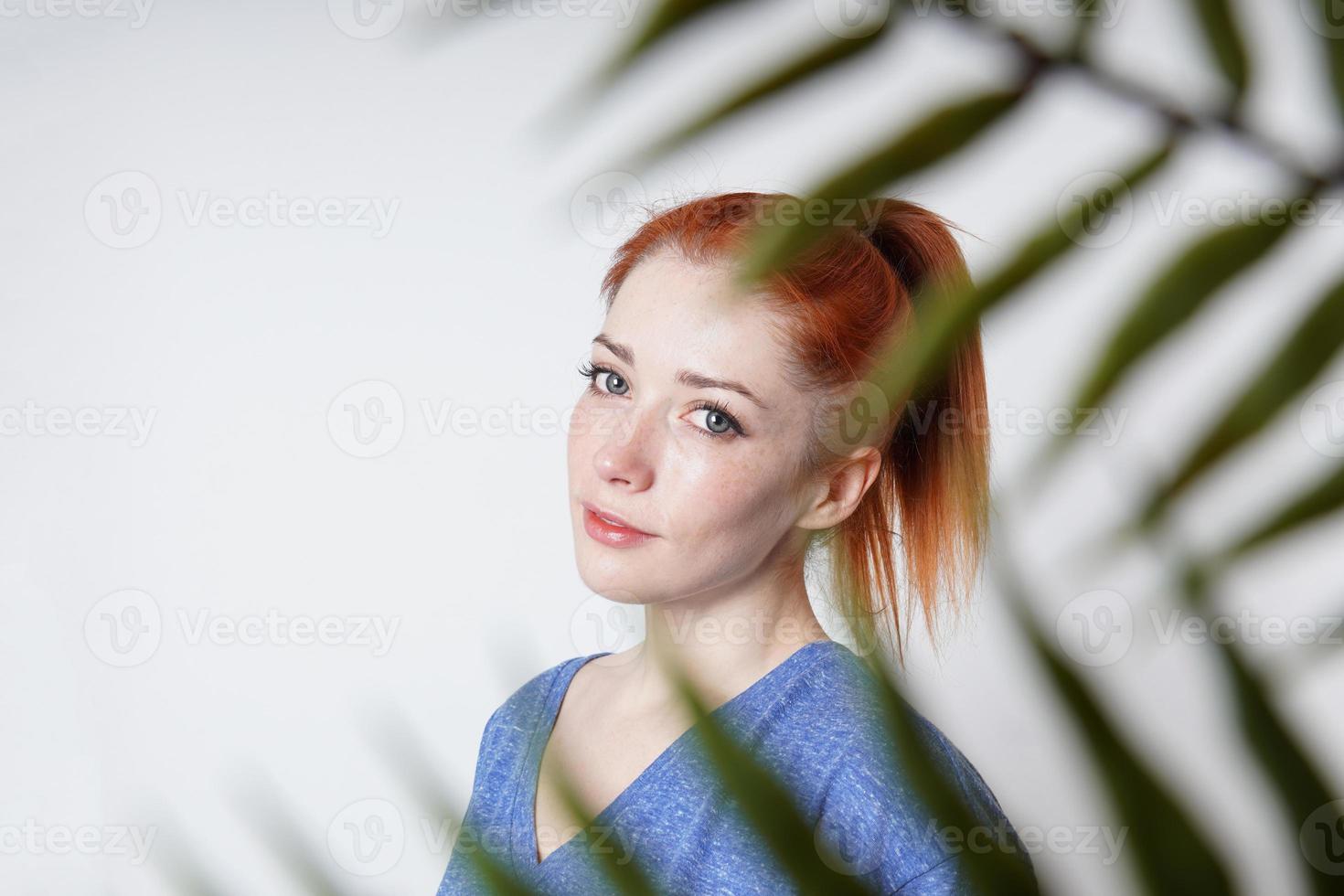 retrato interior de una mujer joven disparada a través de hojas de plantas foto