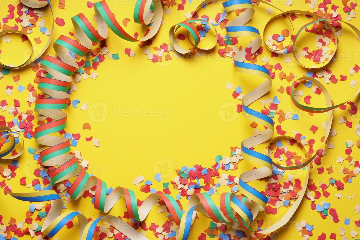 confetti and paper streamer frame on yellow background photo