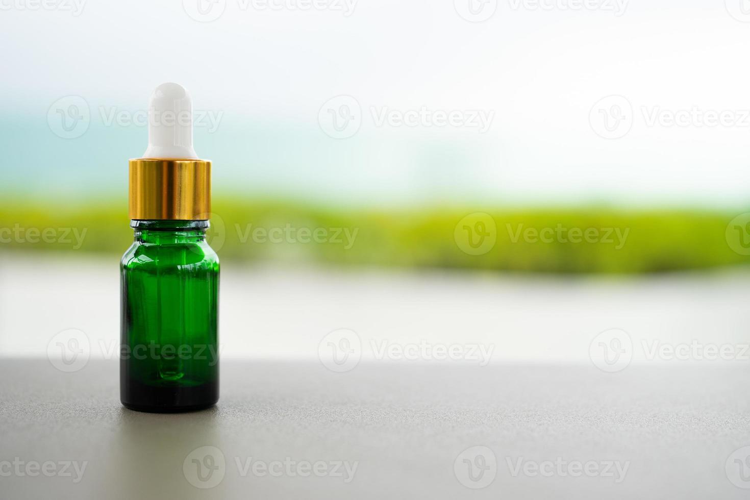 A green glass bottle with dropper on the table. Concept of aroma oil, cosmetic, and beauty skin. photo