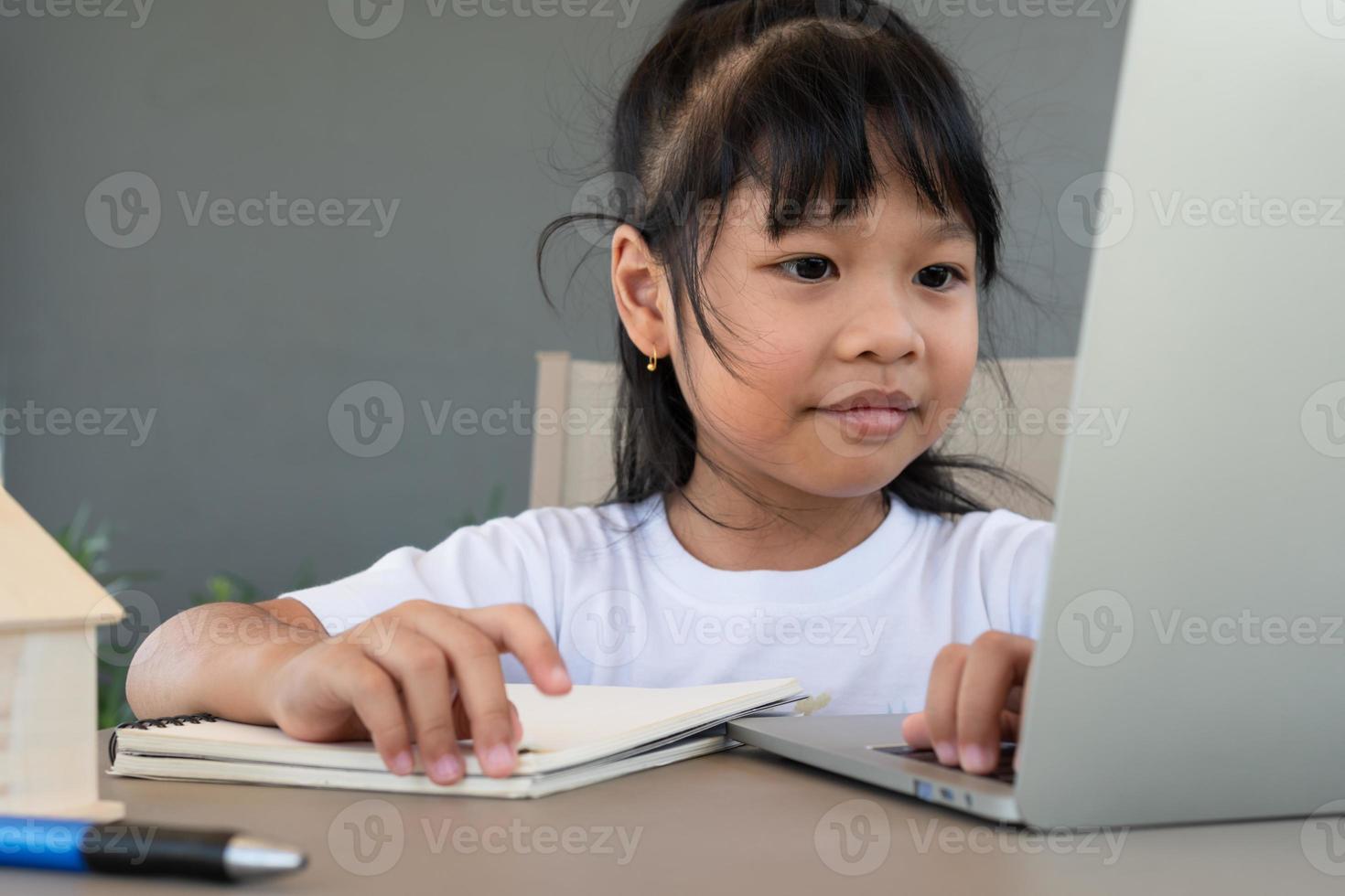 estudiante asiática que usa la computadora portátil para la clase de aprendizaje en línea y hace la tarea en casa, educación y aprendizaje a distancia para el concepto de educación en el hogar para niños foto