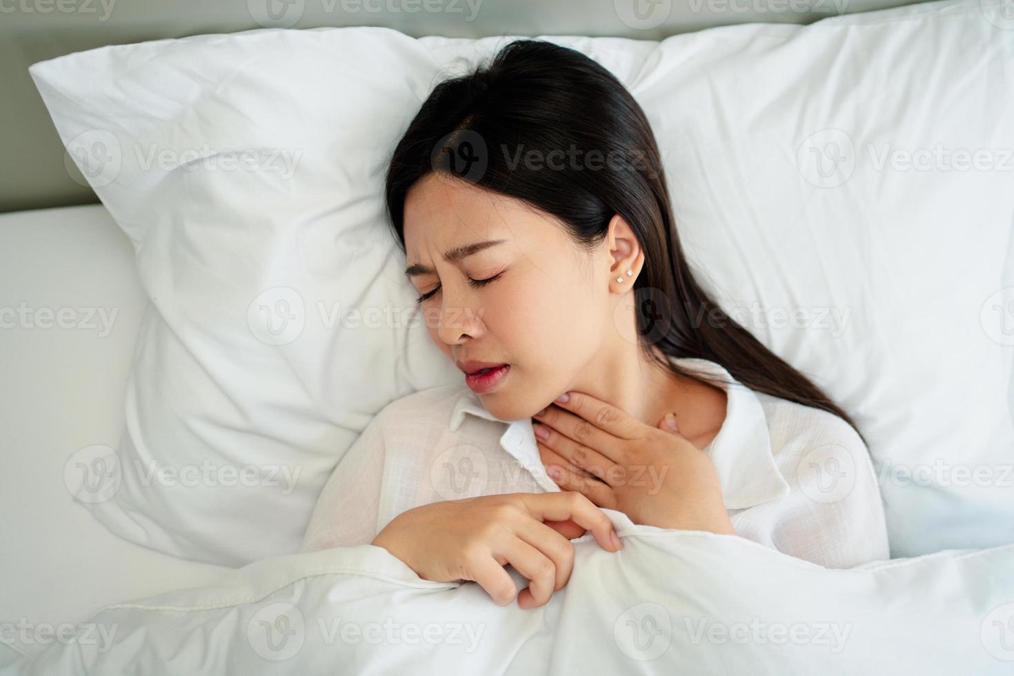 Unhappy exhausted woman closed eyes lying in bed cause of Headache, sore throat and tired, Concept of recuperation from illness, feeling unwell and healthcare. photo