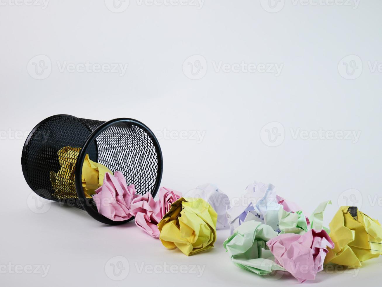 A small black basket made of round iron fell down. It is used to put the trash, documents that are not working and are overflowing to the outside. In the white background there is a copy space. photo