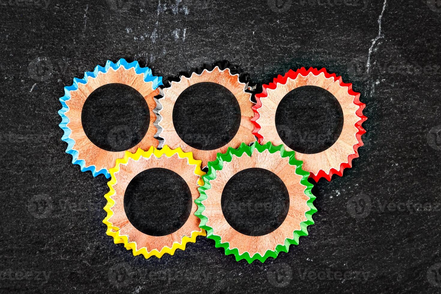 Olympic rings symbol made with color pencil shavings on a stone slate. Horizontal image. photo