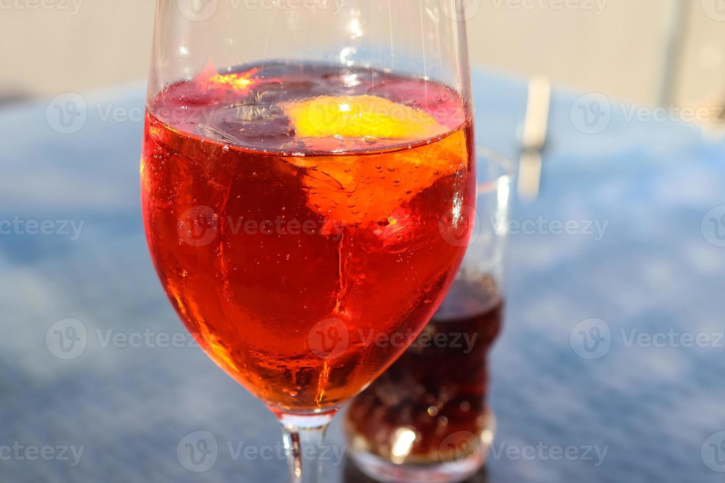 Refreshing orange summer cocktails with cola and ice against a blue sky background. Close up view. photo