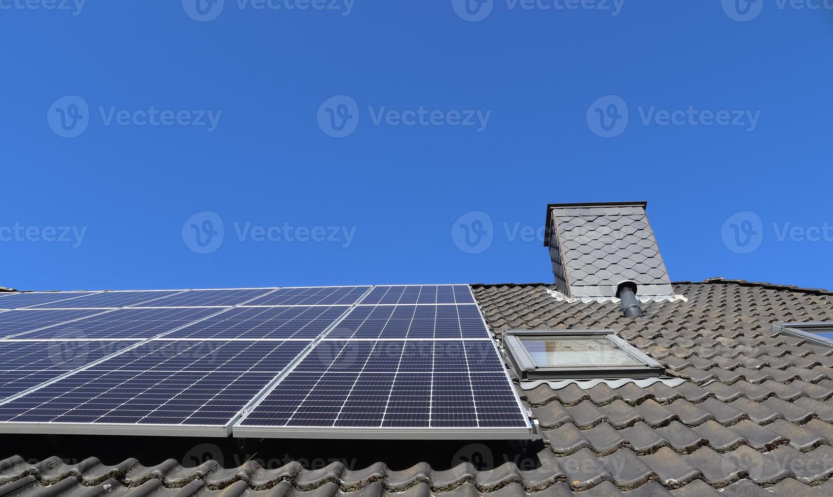 Solar panels producing clean energy on a roof of a residential house photo