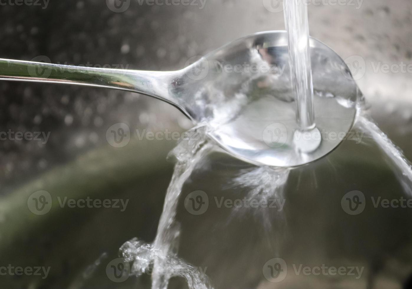 Running water from a water tap into the drain of a chrome sink. photo