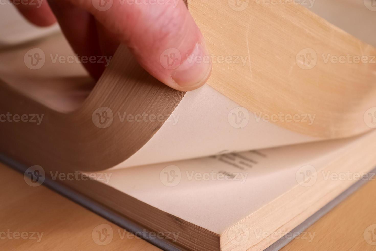 Selective focus view of an old thick german mathematics book with a male hand searching in it. photo