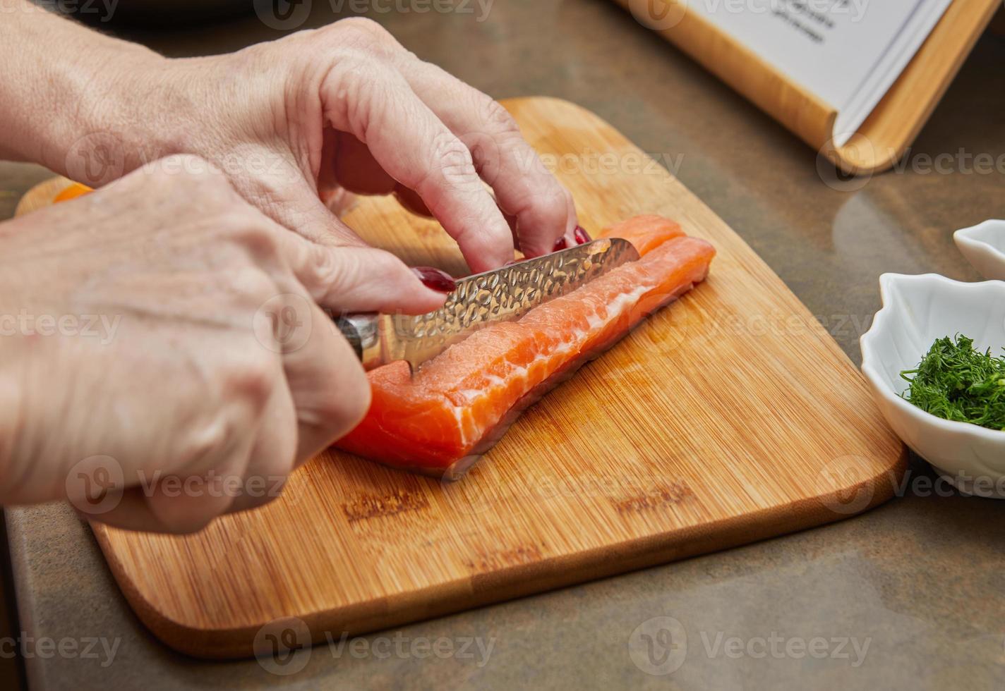 Chef cuts salmon with knife to prepare recipe photo