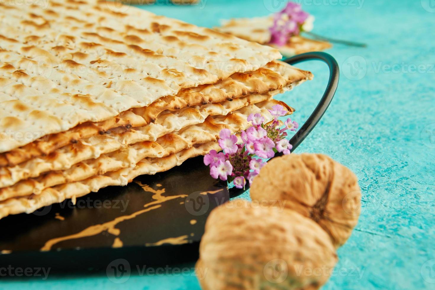 Pesach celebration concept - jewish Passover holiday. Matzah on stand made of marble with walnuts and wildflowers photo