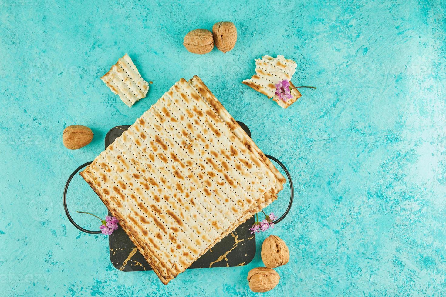 Pesach celebration concept - jewish Passover holiday. Matzah on stand made of marble with walnuts and wildflowers photo