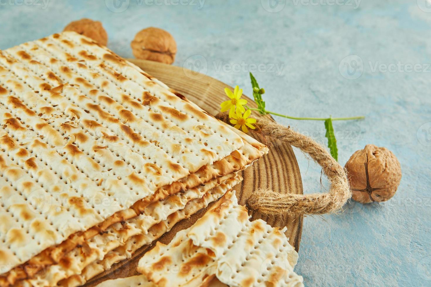 Pesach celebration concept - jewish Passover holiday. Matzah on wooden stand with nuts and wildflowers photo