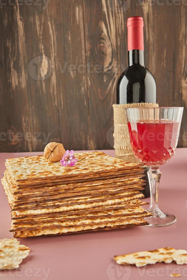 Pesah celebration concept - jewish Passover holiday. Stack of matzah, bottle of wine with glass and nuts photo