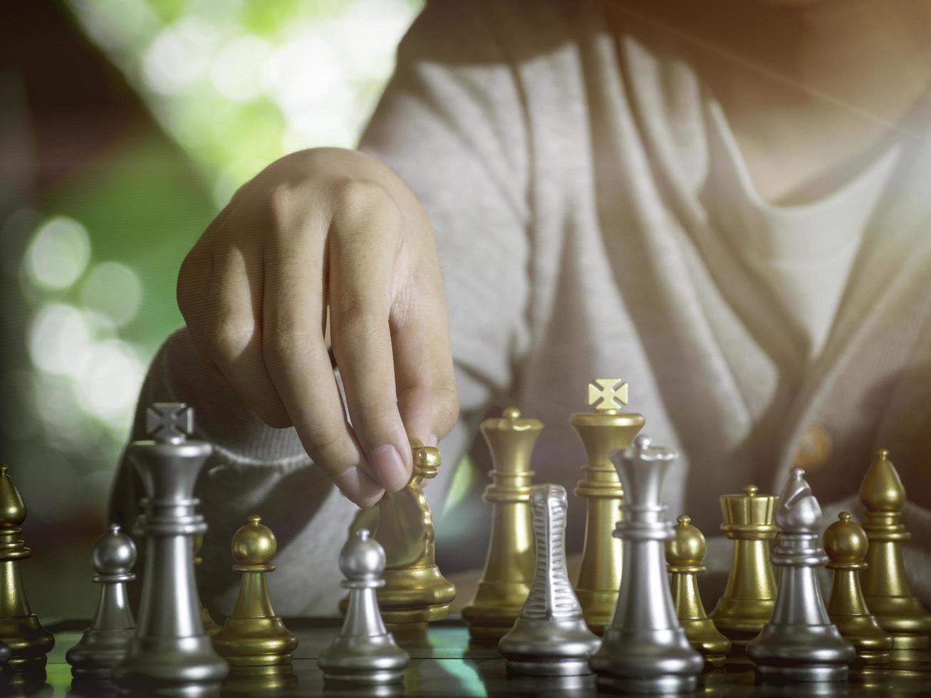 Hand businessman moving the golden knight chess fighting silver knight with fire sparks chess on chess board to successfully in the competition. Management or leadership strategy and teamwork concept. photo