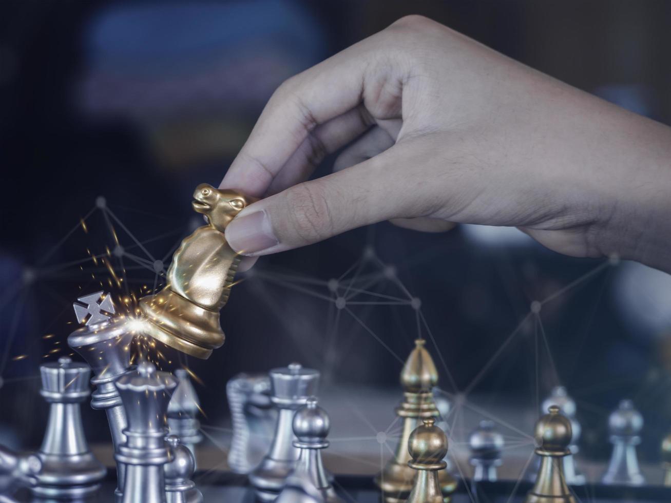 Hand businessman moving the golden knight chess fighting silver knight with fire sparks chess on chess board to successfully in the competition. Management or leadership strategy and teamwork concept. photo