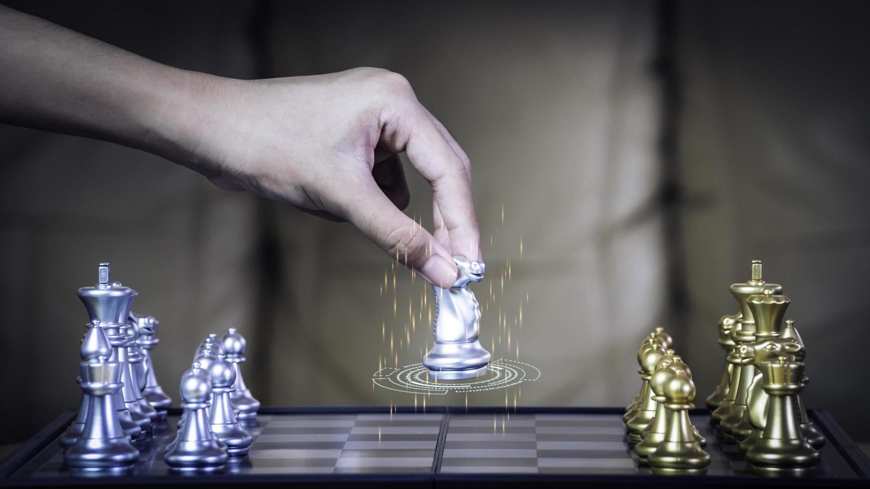 Hand businessman moving the golden knight chess fighting silver knight with fire sparks chess on chess board to successfully in the competition. Management or leadership strategy and teamwork concept. photo