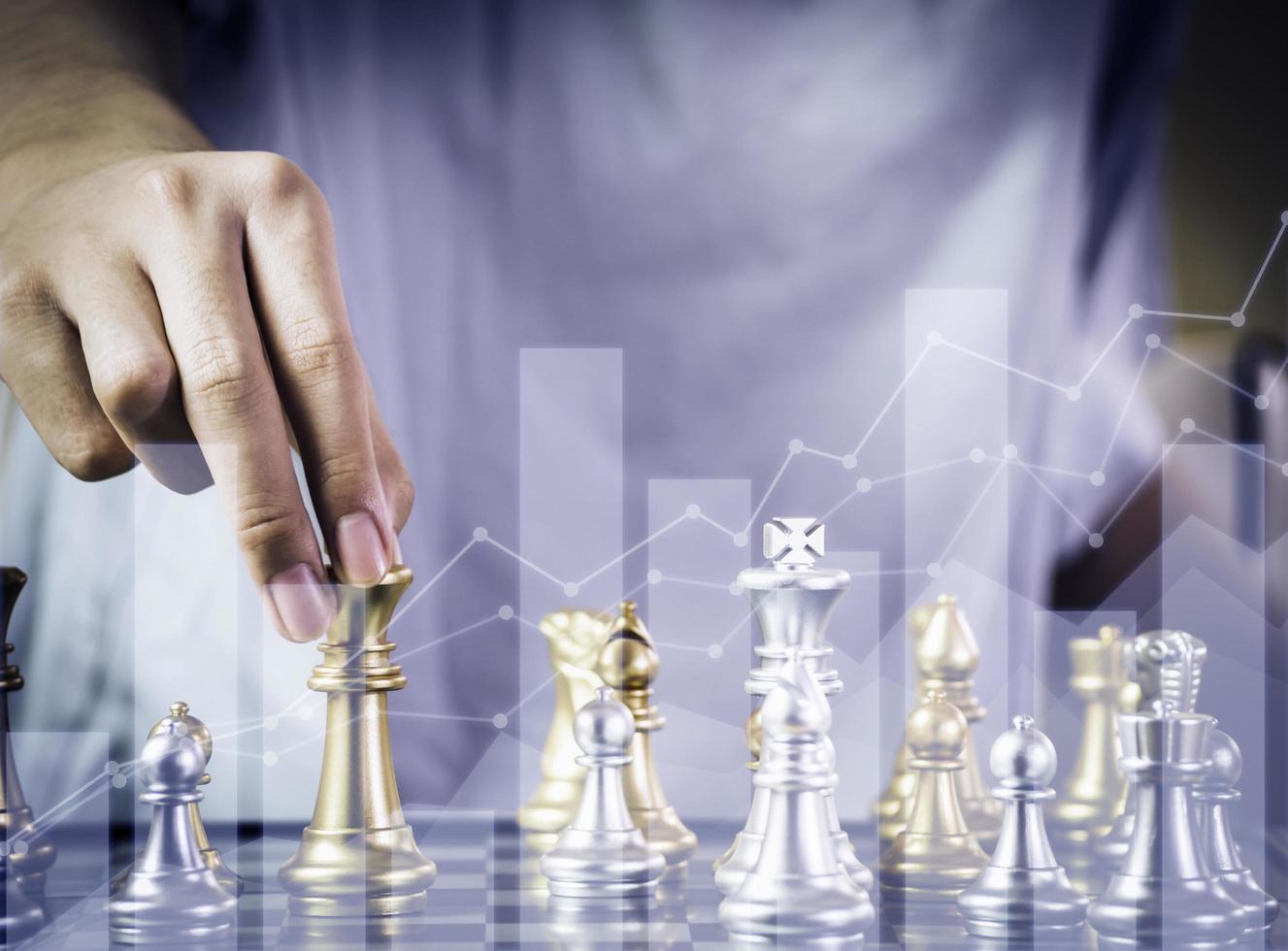 Hand businessman moving the golden knight chess fighting silver knight with fire sparks chess on chess board to successfully in the competition. Management or leadership strategy and teamwork concept. photo