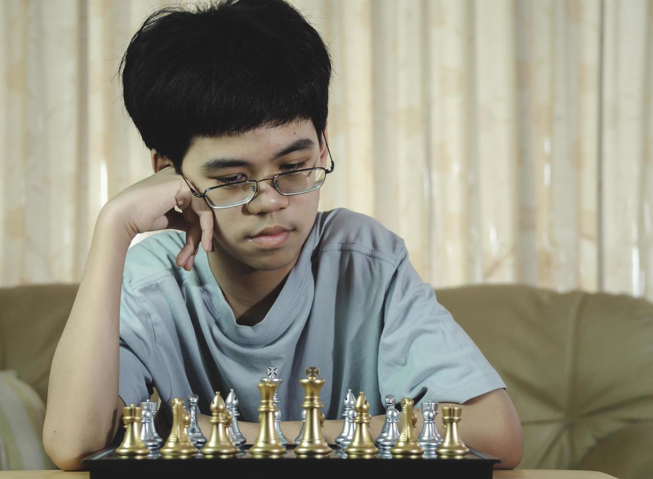 niño serio concentrado que desarrolla gambito de ajedrez, estrategia, juego de mesa para ganar concentración inteligente y niño pensante mientras juega al ajedrez. concepto de aprendizaje, táctica y análisis. foto