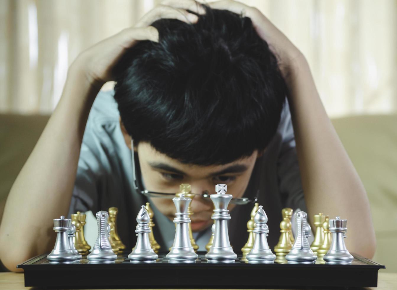 niño serio concentrado que desarrolla gambito de ajedrez, estrategia, juego de mesa para ganar concentración inteligente y niño pensante mientras juega al ajedrez. concepto de aprendizaje, táctica y análisis. foto