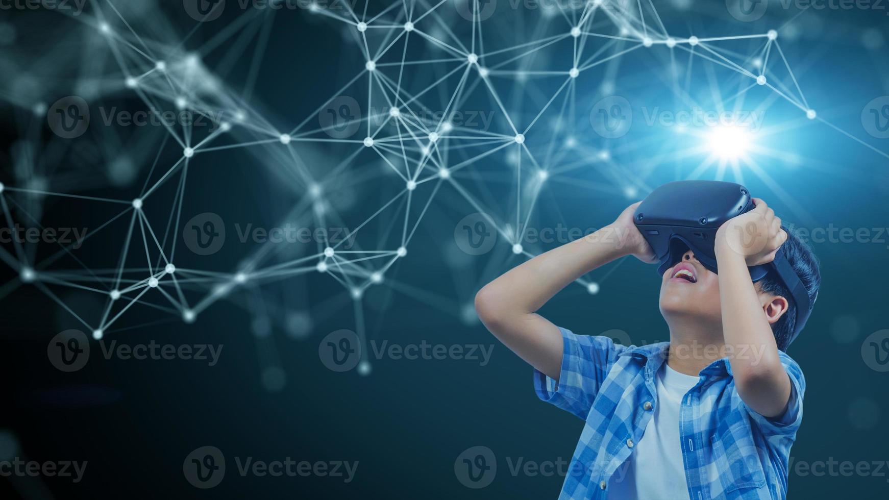 Boy wearing virtual reality glasses in modern interior design studio and trying to touch dots network and earth map or something appear in VR with exciting.Flares effect, blurred background concept. photo