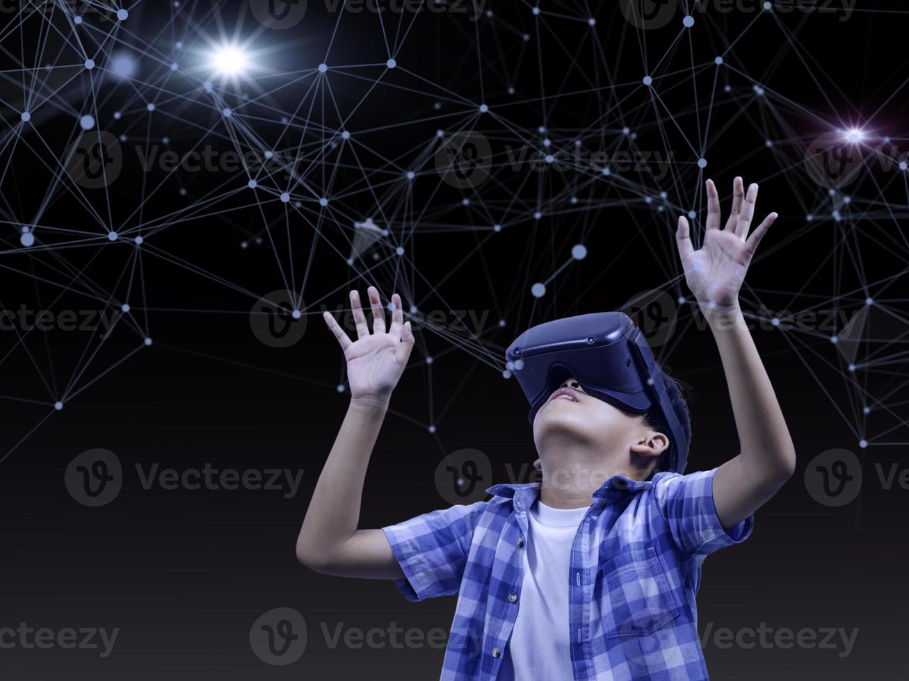 Boy wearing virtual reality glasses in modern interior design studio and trying to touch dots network and earth map or something appear in VR with exciting.Flares effect, blurred background concept. photo