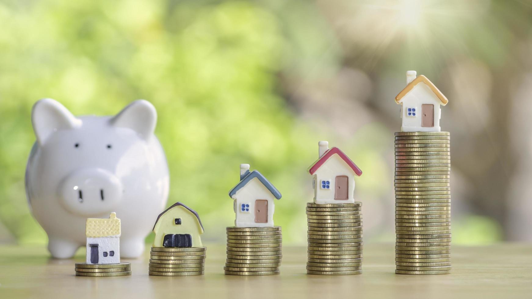 Coins stack 4 rows of gold coins and a white piggy bank placed on a wooden table to save money invest for future. Concept for loan, property ladder, financial, real estate investment, taxes and bonus. photo