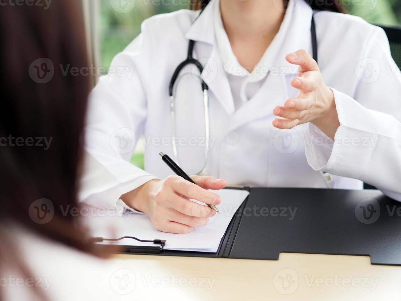 A close-up of the hand of a female doctor or nurse holding a pen is talking or explaining information or something for a patient. photo