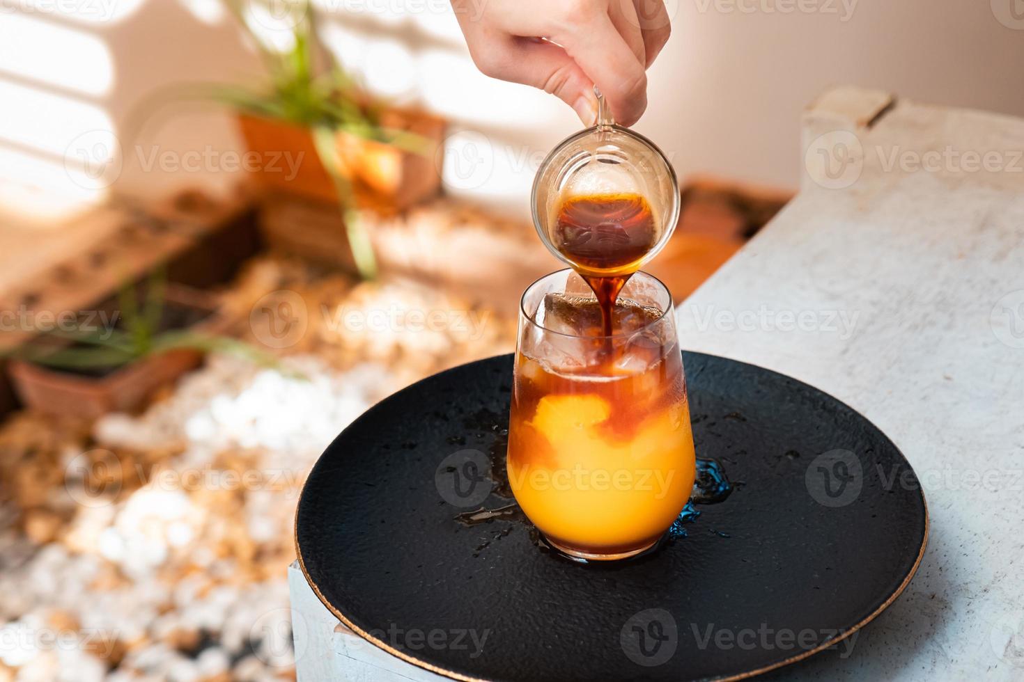 vaso de espresso con jugo de naranja sobre una mesa de madera y espacio para copiar, cóctel de verano, café frío o té negro. verter bebida fría. foto