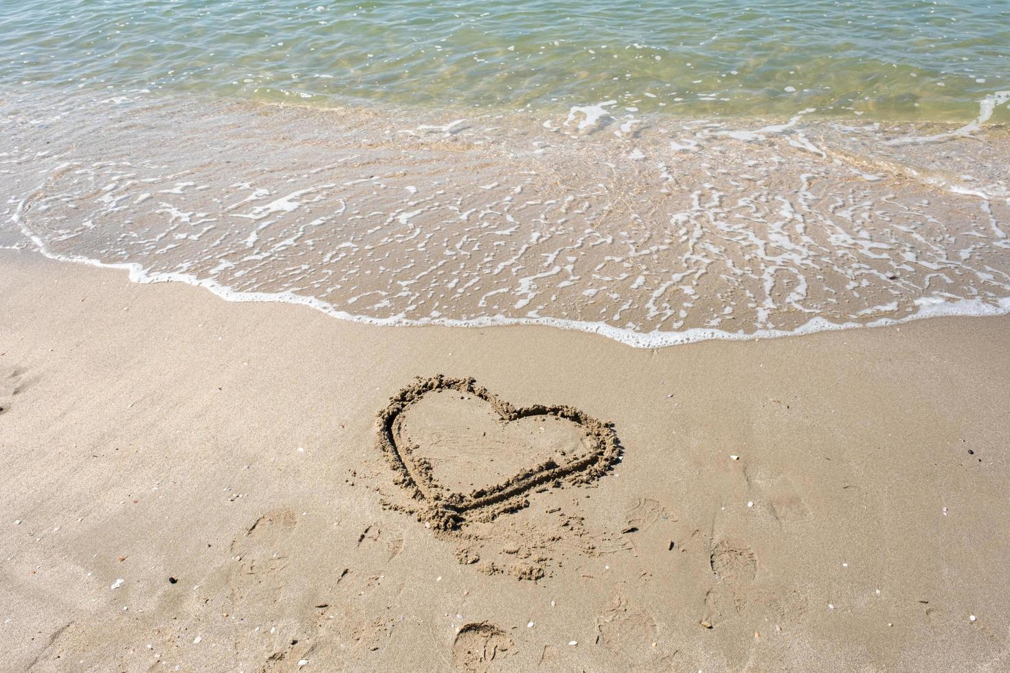 blurred of drawing heart on a yellow sand at a beautiful seascape background. Horizontal composition. photo