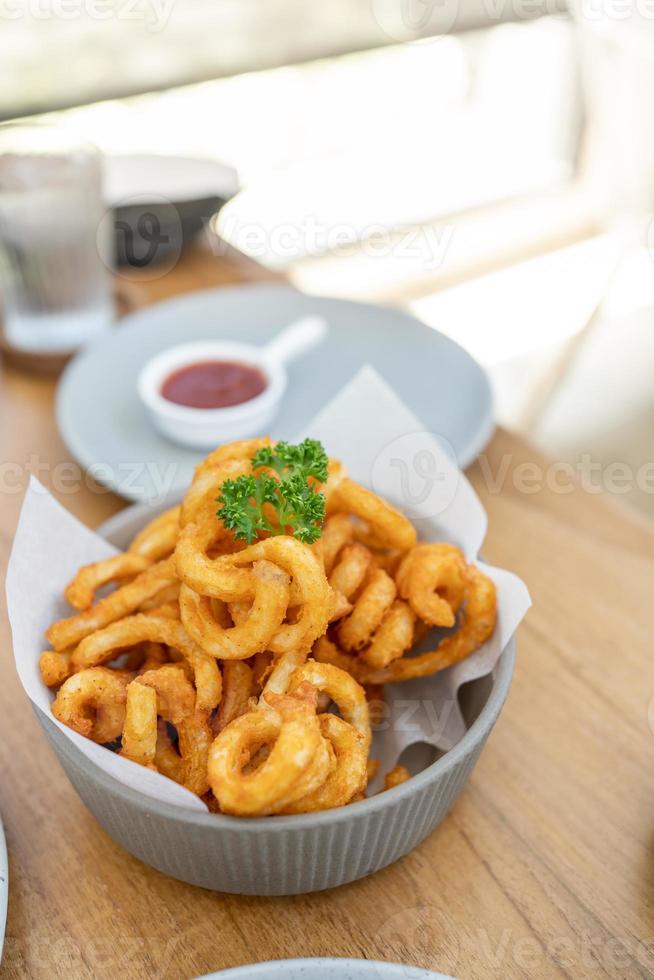 Golden Spicy Seasoned Curly Fries on rustic plate. fast food snack with ketchup on restaurant background. Unhealthy junk food. ready to eat photo