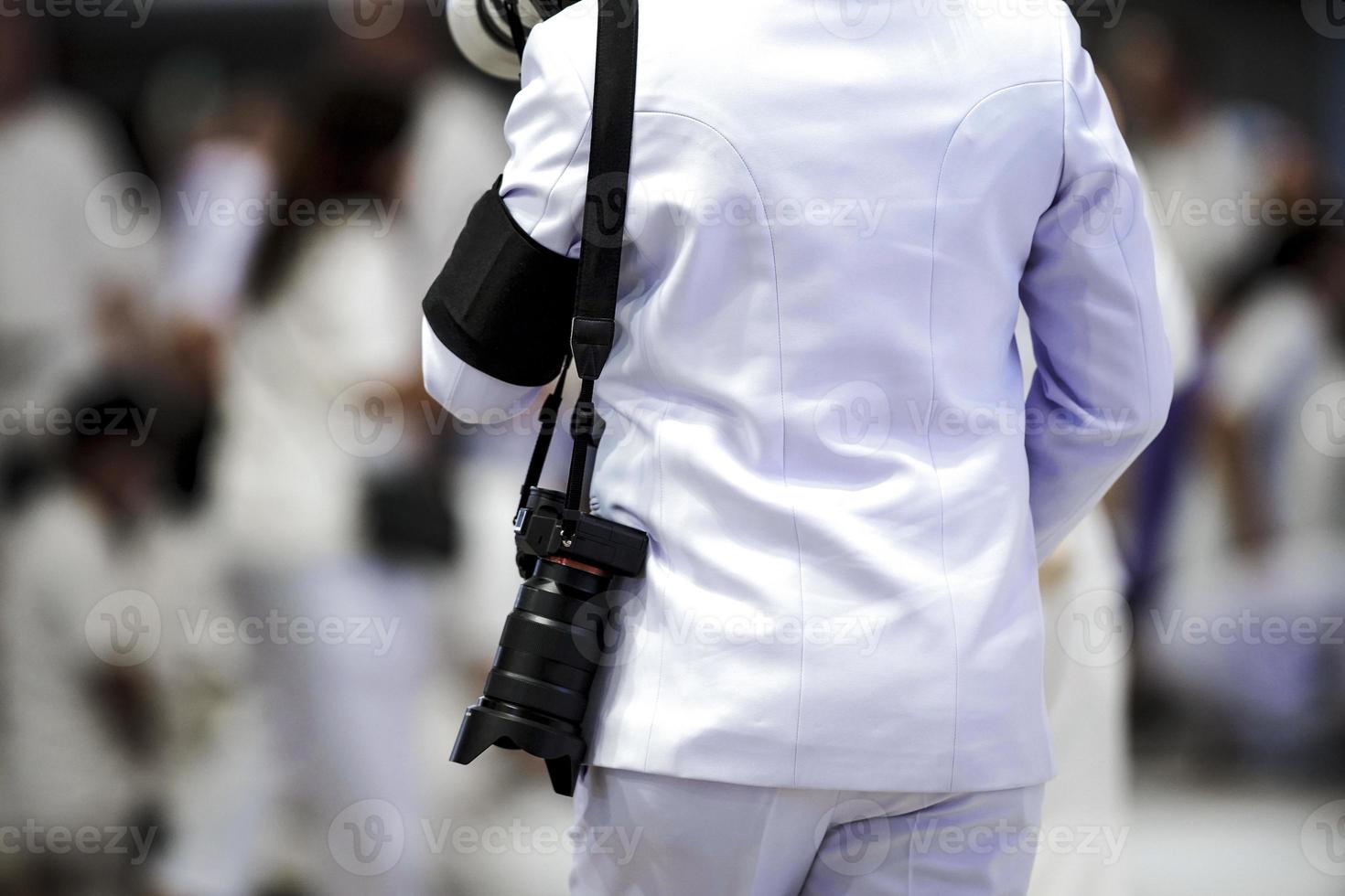 Professional cameraman back hanging strap and mirrorless camera with blur crowd background. photo