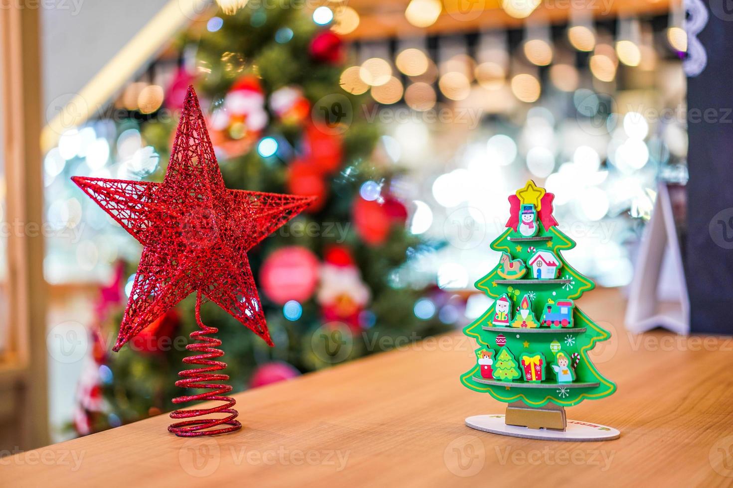 Red star  Christmas tree paper craft decoration on the wood table with blur big Christmas tree behide. photo