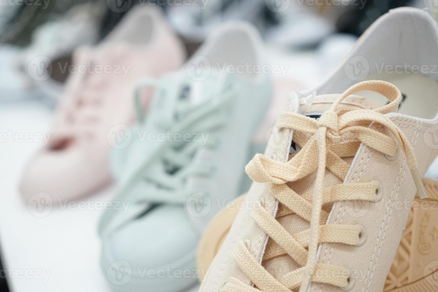 zapatillas de deporte en colores pastel en el estante de exhibición para la venta en la tienda de deportes en los grandes almacenes. foto