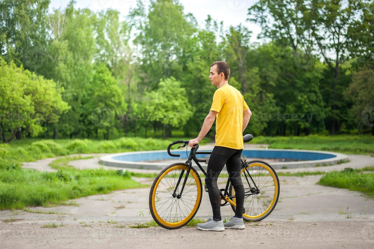 A young Man stopped to rest With his Bicycle in a public Park. photo