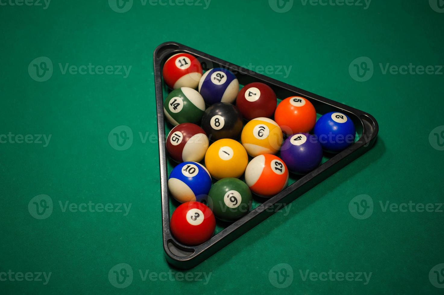 Sport billiard balls set arranged in shape of triangle on green billiard table in pub photo