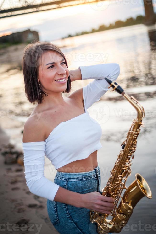 Woman playing the saxophone at sunset photo